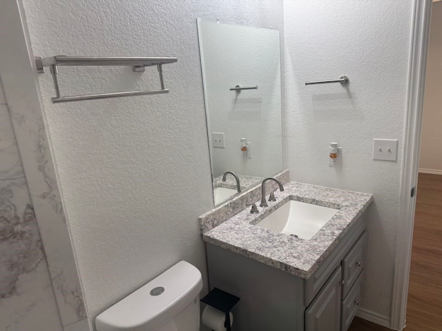 bathroom with hardwood / wood-style flooring, vanity, and toilet