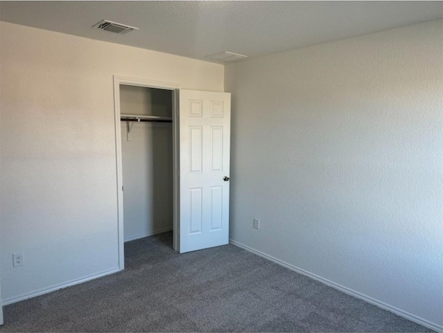 unfurnished bedroom with dark carpet and a closet