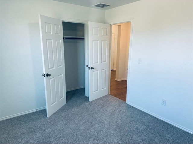 unfurnished bedroom with a closet and dark carpet