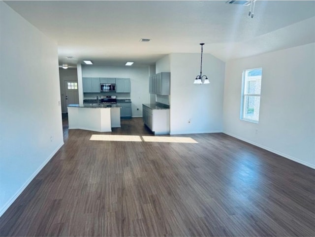 unfurnished living room featuring vaulted ceiling, sink, dark hardwood / wood-style floors, and an inviting chandelier