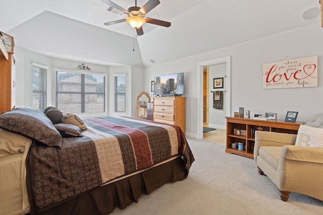 bedroom with light carpet, connected bathroom, vaulted ceiling, and ceiling fan