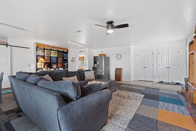 living room featuring ceiling fan and a barn door