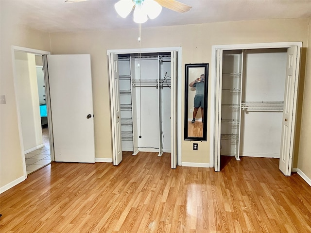 unfurnished bedroom featuring light hardwood / wood-style floors, two closets, and ceiling fan