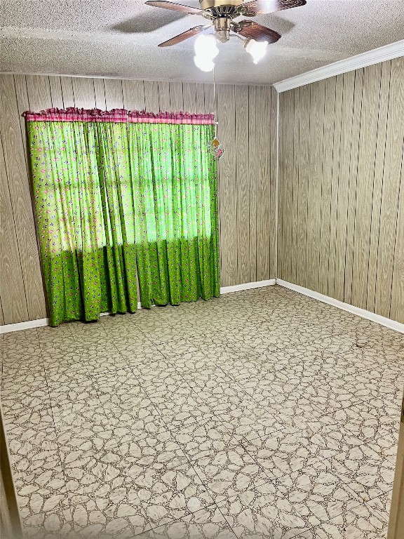 empty room featuring wood walls, a textured ceiling, and ceiling fan