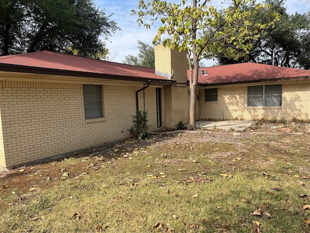 1133 W Bell St, Bartlett, TX 76511 - rear view of house featuring brick siding, a lawn, a chimney, and a patio