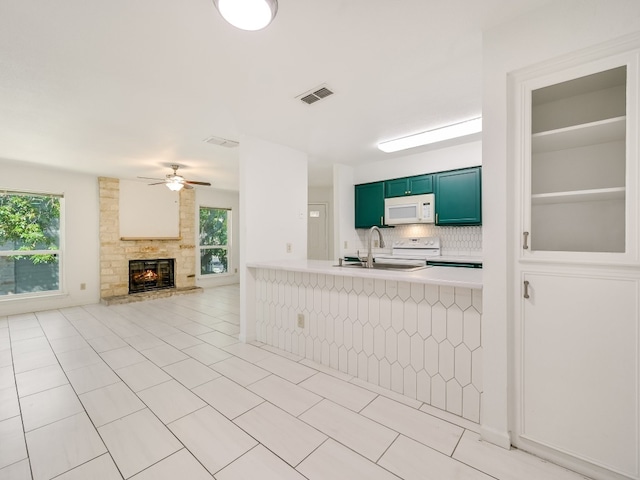 kitchen with a wealth of natural light, sink, kitchen peninsula, and white appliances