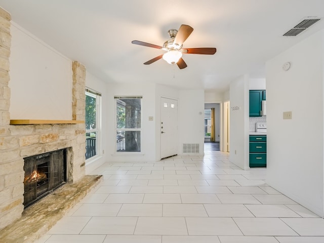 unfurnished living room with a stone fireplace, light tile patterned flooring, and ceiling fan