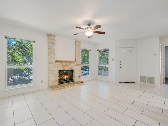 unfurnished living room with ceiling fan, light tile patterned flooring, and a fireplace