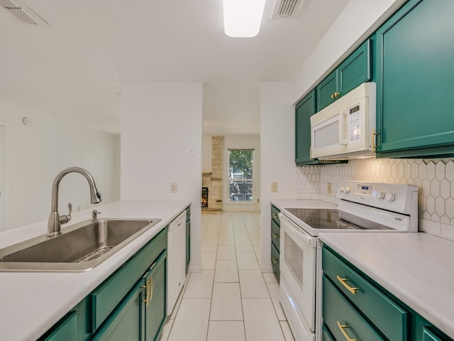 kitchen with light tile patterned flooring, sink, a fireplace, green cabinetry, and white appliances