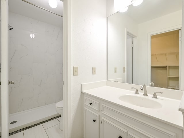 bathroom with vanity, toilet, and tiled shower