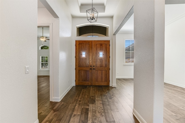 foyer entrance with ornamental molding, hardwood / wood-style flooring, and ceiling fan with notable chandelier