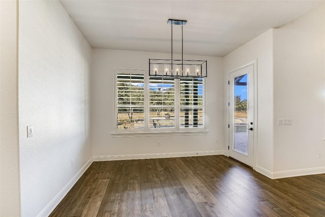 unfurnished dining area with a notable chandelier and dark hardwood / wood-style flooring