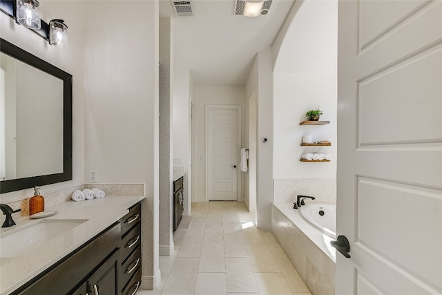 bathroom with vanity, a relaxing tiled tub, and tile patterned flooring