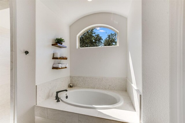 bathroom with a relaxing tiled tub