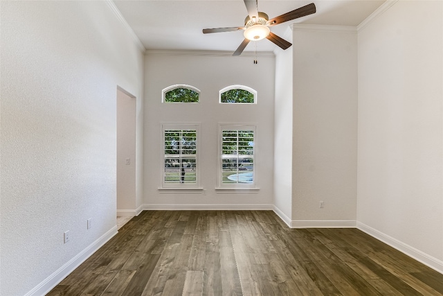 empty room with crown molding, dark hardwood / wood-style floors, a towering ceiling, and ceiling fan