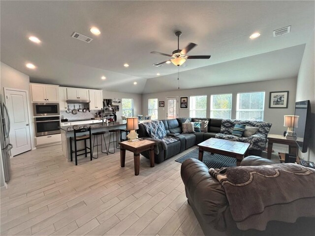 living room with vaulted ceiling, ceiling fan, and light hardwood / wood-style flooring