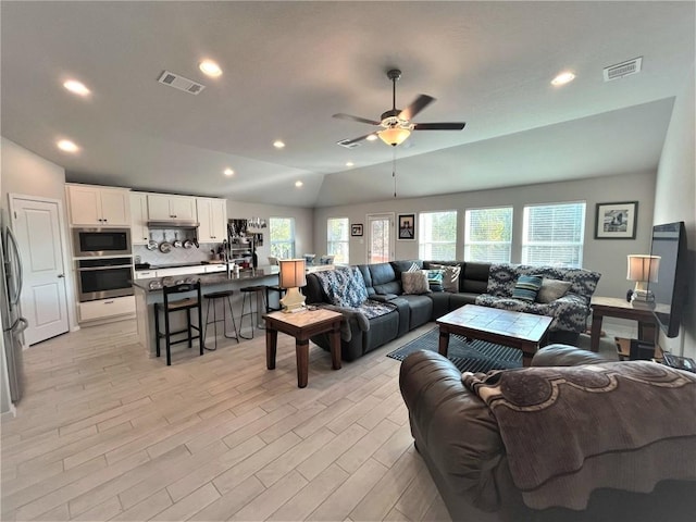 living area featuring visible vents, vaulted ceiling, recessed lighting, light wood-style flooring, and a ceiling fan