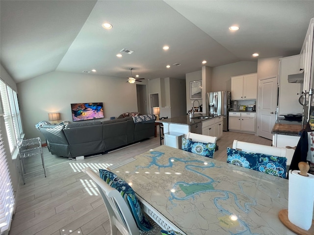 dining area featuring vaulted ceiling, ceiling fan, light wood-type flooring, and sink