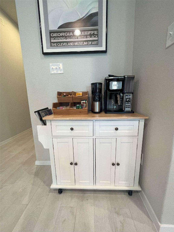 bar featuring white cabinetry and light hardwood / wood-style flooring