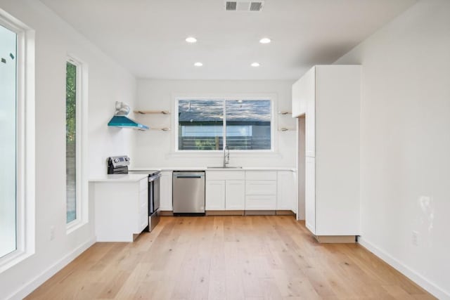 kitchen with light wood-type flooring, appliances with stainless steel finishes, sink, and white cabinets