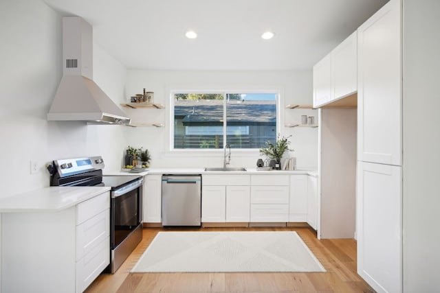 kitchen featuring sink, white cabinetry, island range hood, stainless steel appliances, and light hardwood / wood-style floors