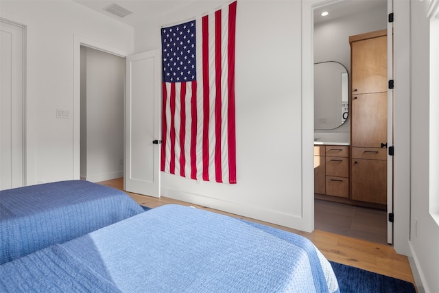 bedroom featuring ensuite bathroom and light wood-type flooring