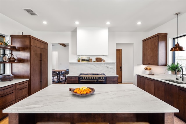 kitchen featuring high end stainless steel range oven, dark brown cabinets, a kitchen island, and sink