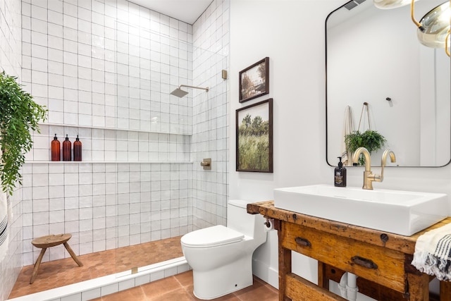 bathroom with tile patterned floors, toilet, a tile shower, and vanity