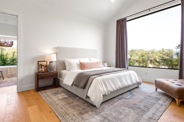 bedroom with connected bathroom, light hardwood / wood-style flooring, and lofted ceiling