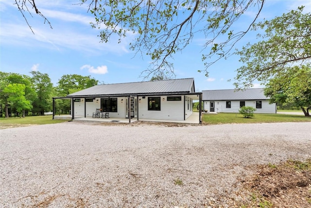 view of front of property with metal roof, driveway, and a front lawn