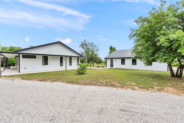 view of front of home with metal roof and a front lawn