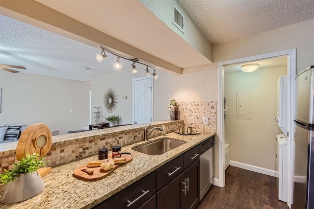 kitchen with backsplash, sink, light stone countertops, dark brown cabinetry, and stainless steel appliances