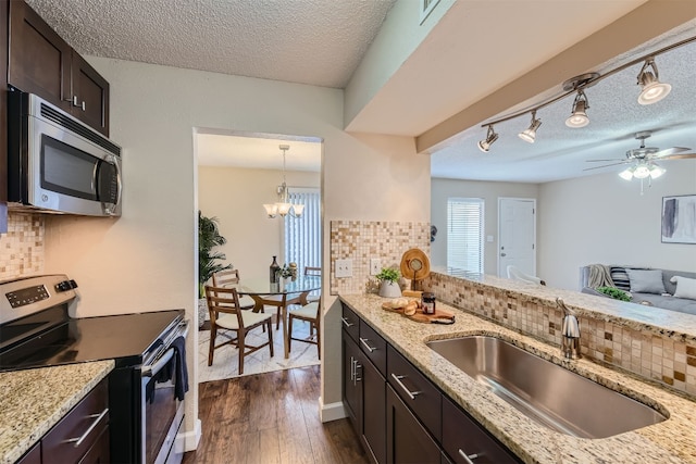 kitchen featuring dark brown cabinets, rail lighting, stainless steel appliances, and tasteful backsplash