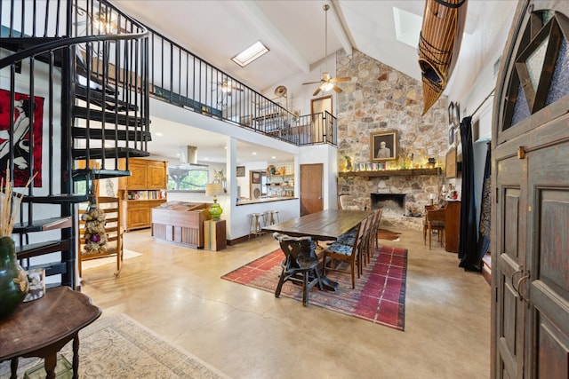 dining space featuring a stone fireplace, beamed ceiling, high vaulted ceiling, and ceiling fan