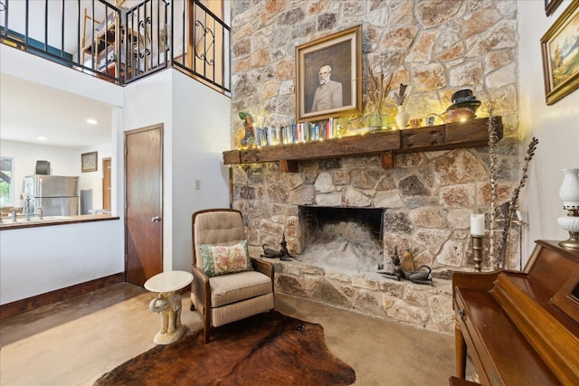 sitting room with concrete floors and a stone fireplace