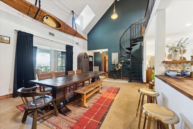 dining space with a towering ceiling and a skylight