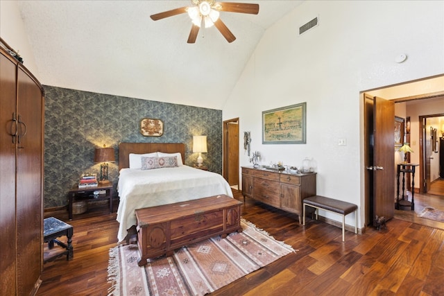 bedroom featuring dark wood-type flooring, a barn door, high vaulted ceiling, and ceiling fan