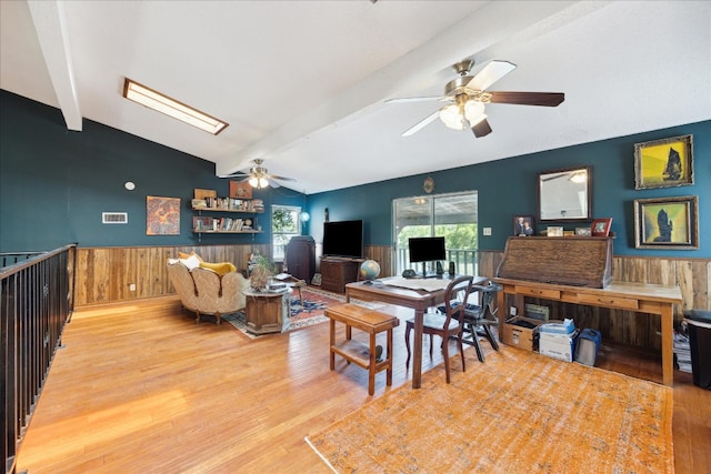 dining area with wood walls, lofted ceiling with beams, hardwood / wood-style flooring, and ceiling fan