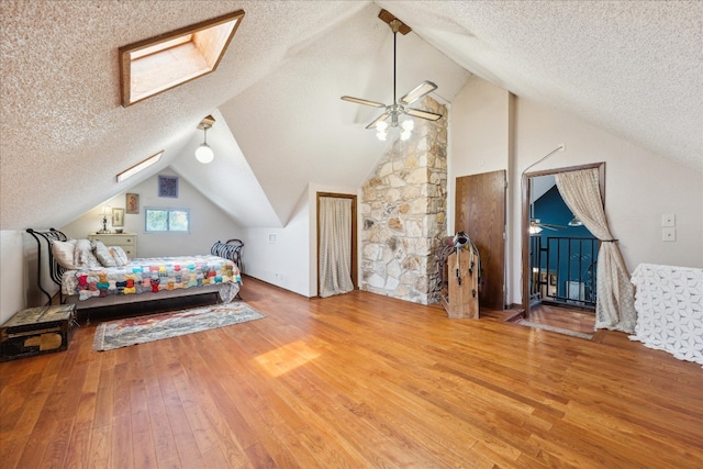 bedroom with lofted ceiling with skylight, a textured ceiling, and hardwood / wood-style flooring