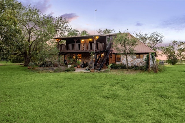 back house at dusk featuring a deck and a lawn