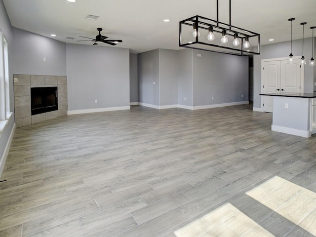 unfurnished living room with a fireplace, ceiling fan, and light hardwood / wood-style floors