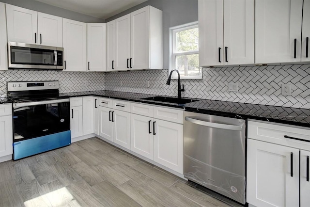 kitchen featuring light wood-type flooring, stainless steel appliances, sink, white cabinets, and decorative backsplash