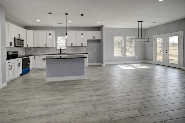 kitchen with appliances with stainless steel finishes, sink, white cabinetry, and hanging light fixtures