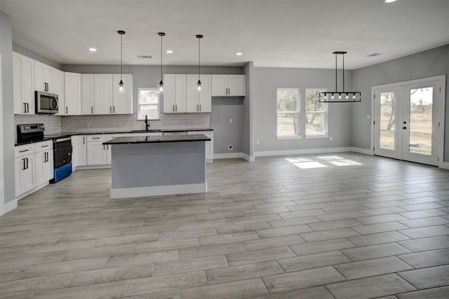 kitchen featuring range with electric stovetop, white cabinetry, a kitchen island, and decorative light fixtures