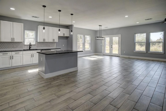 kitchen with a kitchen island, white cabinetry, hanging light fixtures, and backsplash