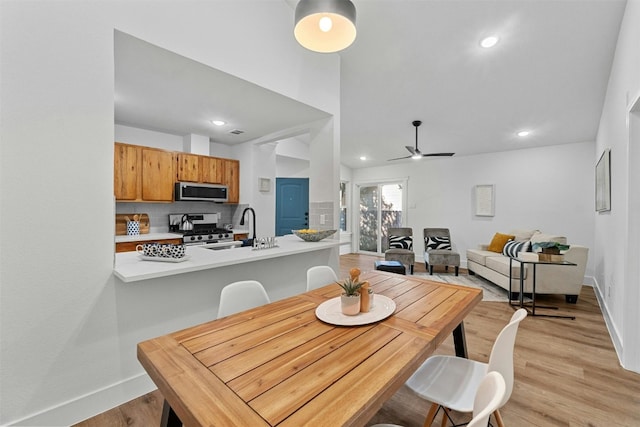 dining area featuring ceiling fan, sink, and light hardwood / wood-style floors