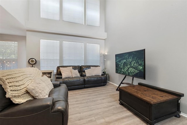 living room featuring a towering ceiling and light wood-type flooring