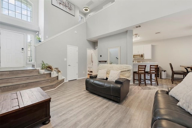 living room featuring light hardwood / wood-style flooring and a high ceiling