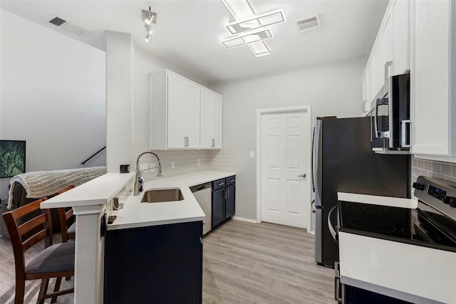 kitchen with stainless steel appliances, tasteful backsplash, a kitchen bar, and white cabinets