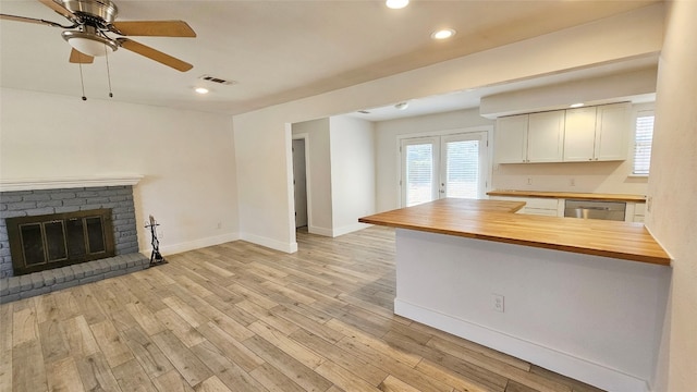 kitchen featuring stainless steel dishwasher, kitchen peninsula, light wood-type flooring, and wood counters